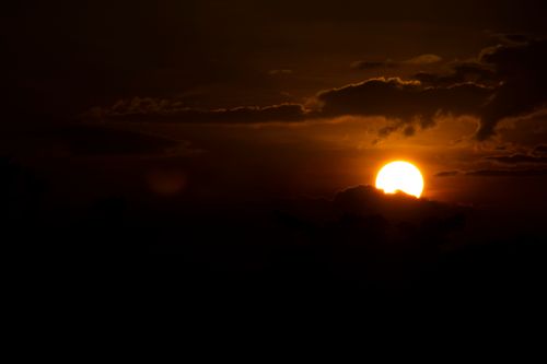 Free A vibrant sunset with dramatic cloud formations casting silhouettes. Perfect for tranquil scenery themes. Stock Photo