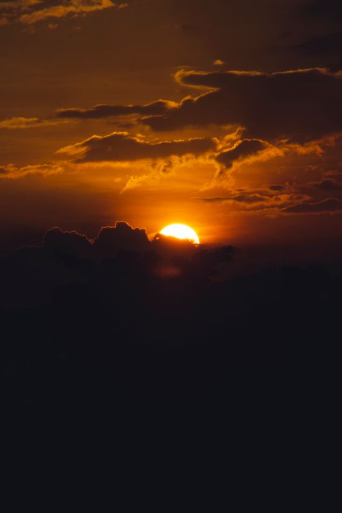 Free Stunning sunset with dramatic clouds, creating a vivid silhouette effect. Stock Photo