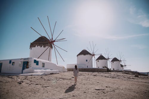 Femme Vêtue D'une Robe Grise Marchant Devant Moulin Sous Le Ciel Bleu