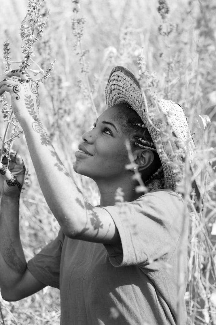 A Woman Wearing Woven Hat Holding The Grass Flowers