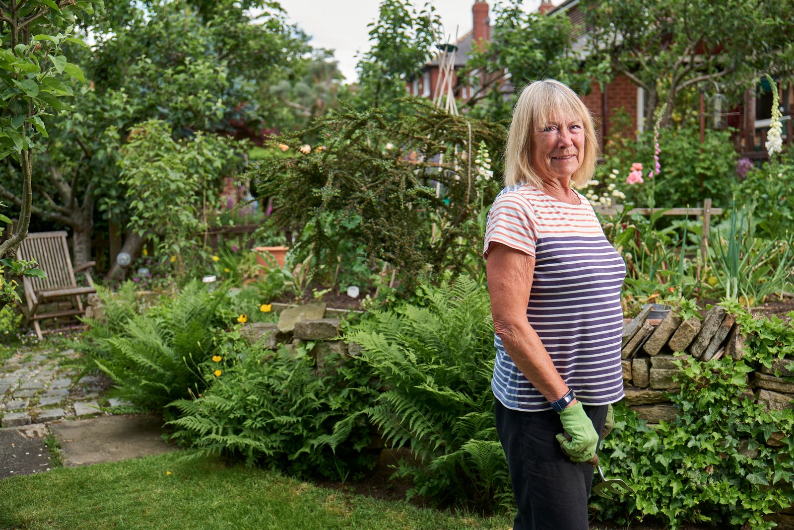 Une dame âgée souriante jardine dans son potager