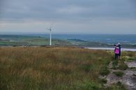Anonymous female travelers looking at windmill in meadow in countryside