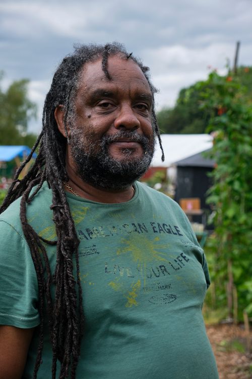 Free Casual outdoor portrait of a man with long dreadlocks in a lush garden setting. Stock Photo