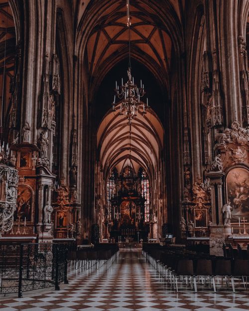 Free A stunning view of a gothic cathedral interior showcasing ornate arches and chandeliers. Stock Photo