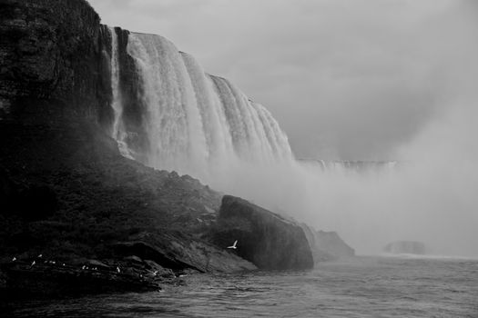 Dramatic black and white photo of Niagara Falls with mist and waterfall in view.