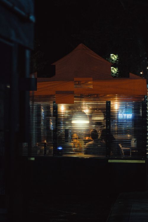 Free Warm, inviting urban bar scene at night, featuring soft light and silhouettes of people indoors. Stock Photo