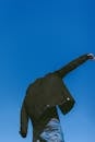 Person in Black Jacket and Blue Denim Pants Standing under Blue Sky