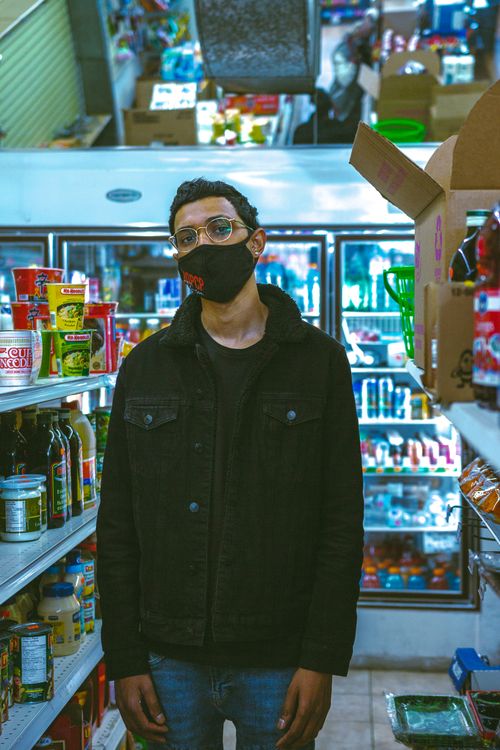 Free Man wearing face mask shopping in grocery aisle with stocked shelves. Stock Photo