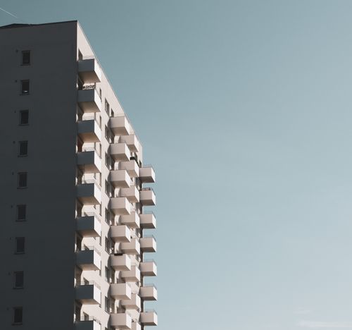 Free Minimalist view of a concrete apartment building with balconies against a clear sky. Stock Photo