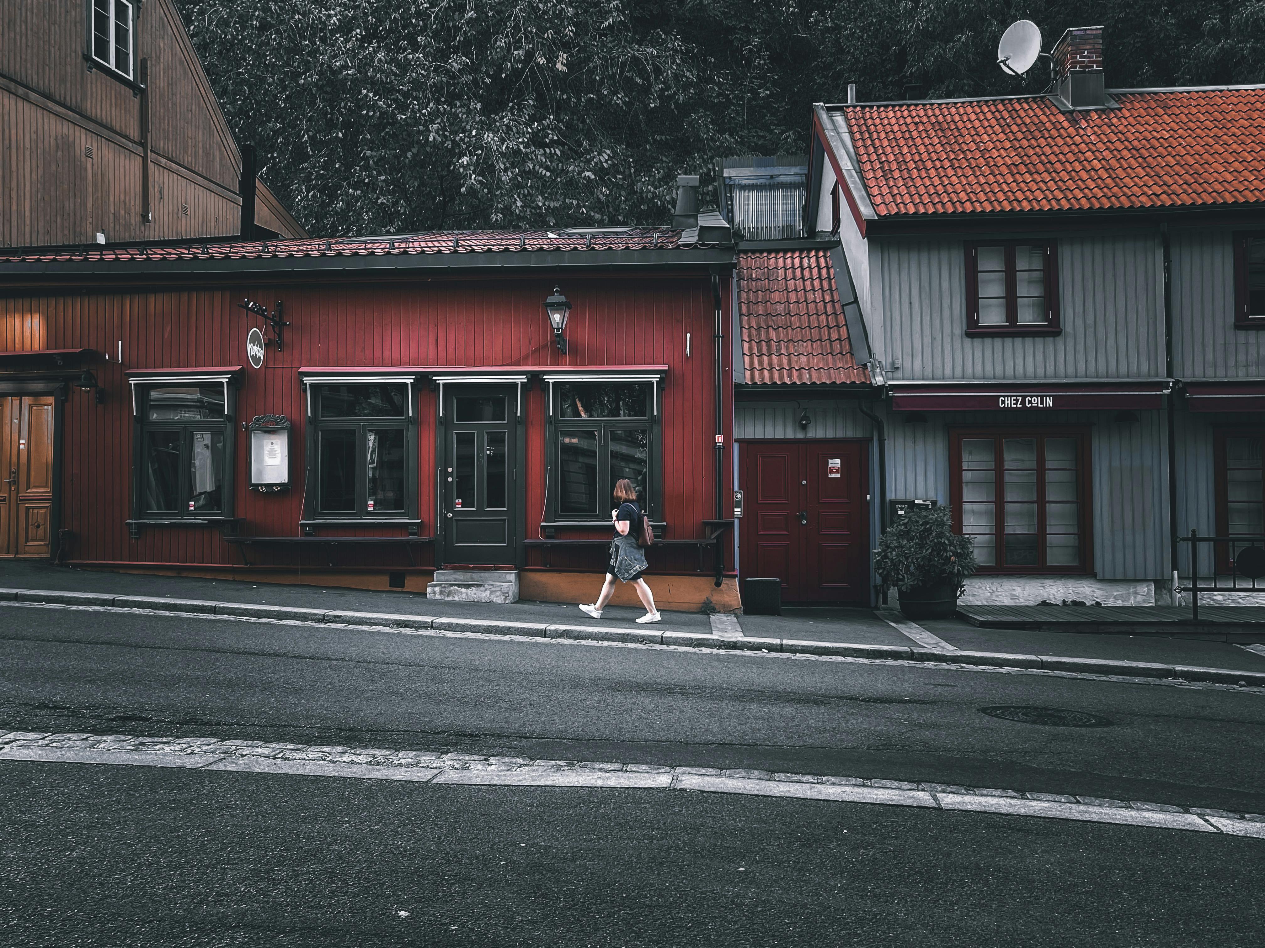 A tranquil street scene featuring a person walking past colorful wooden buildings in a quaint town.