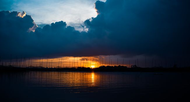 Dramatic clouds and vibrant sunrise reflecting on the calm sea create a picturesque scene.