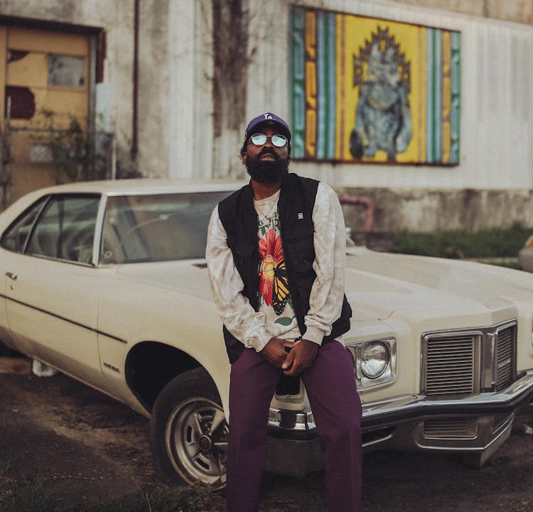 Blackskin Man Sitting On Car And Posing