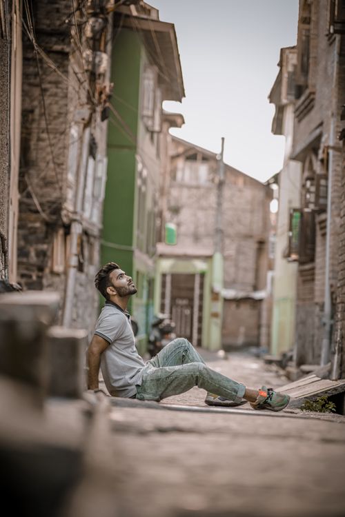 Free Captivating portrait of a man in a rustic alleyway, showcasing street photography and thoughtful pose. Stock Photo