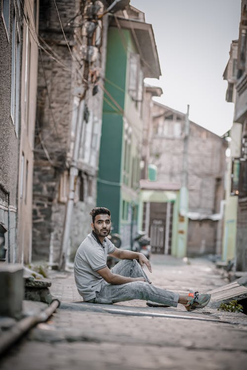 Free A Man in a Polo Shirt Sitting on an Alley Stock Photo