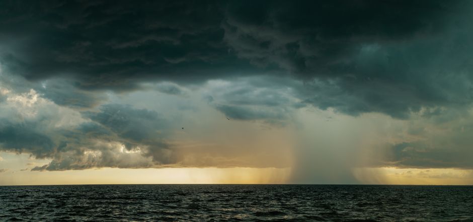 A breathtaking view of storm clouds looming over the ocean at sunset, creating a moody atmosphere.