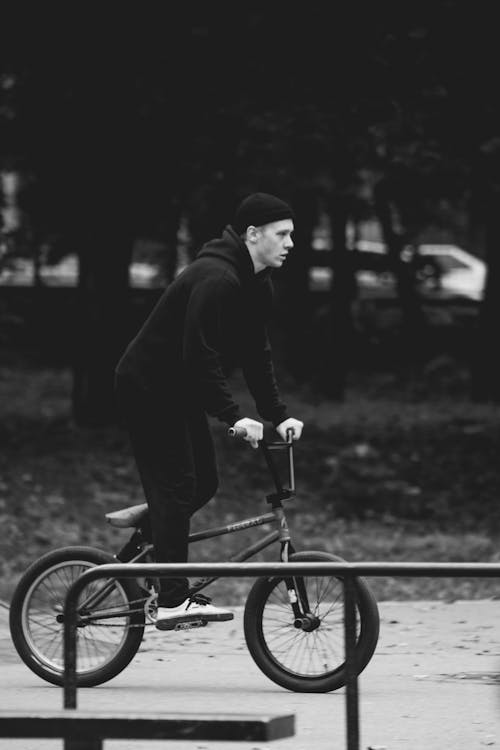 Grayscale Photo of a Man Riding a Bmx Bike