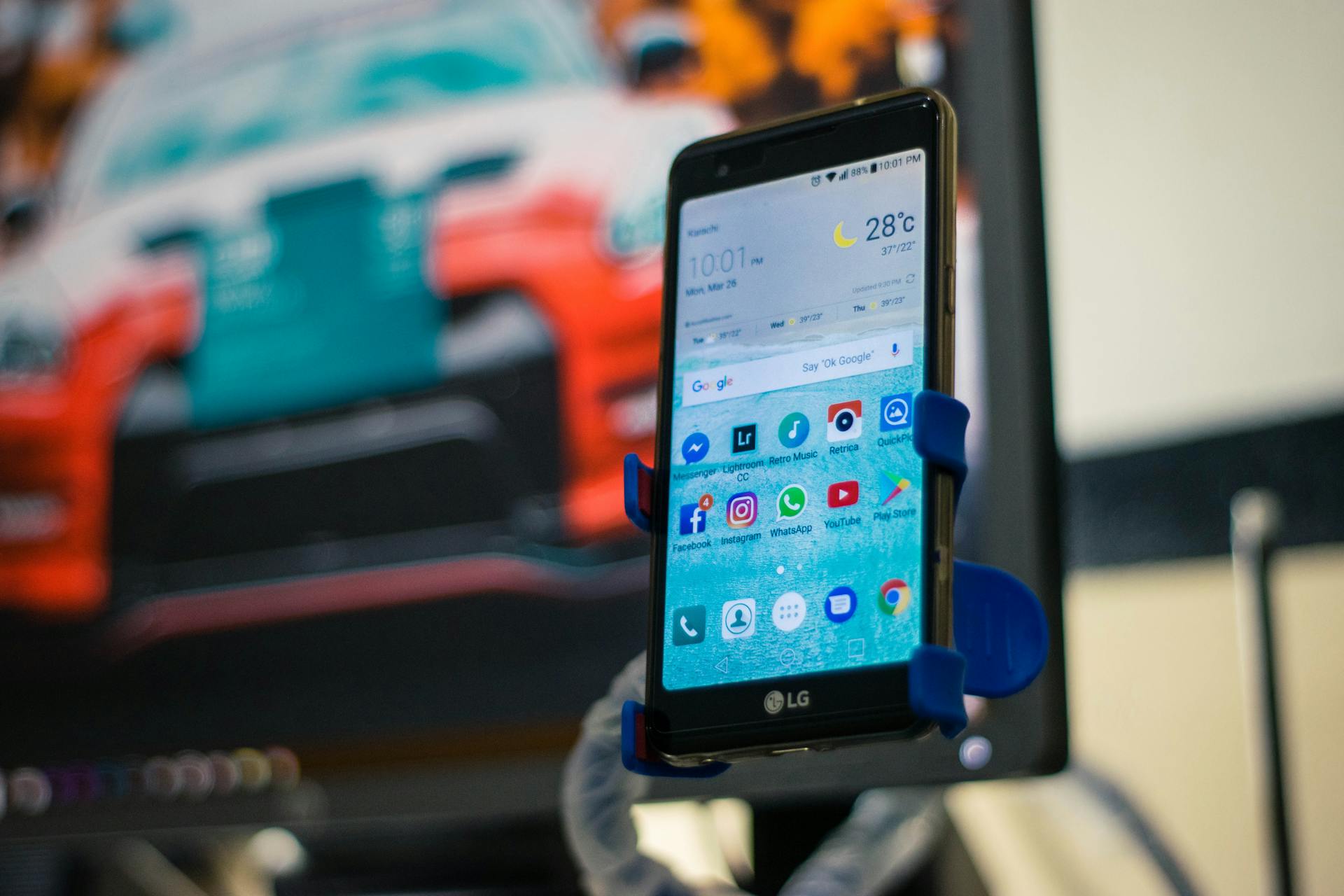 LG smartphone securely mounted in a car holder indoors, displaying various apps on the screen.