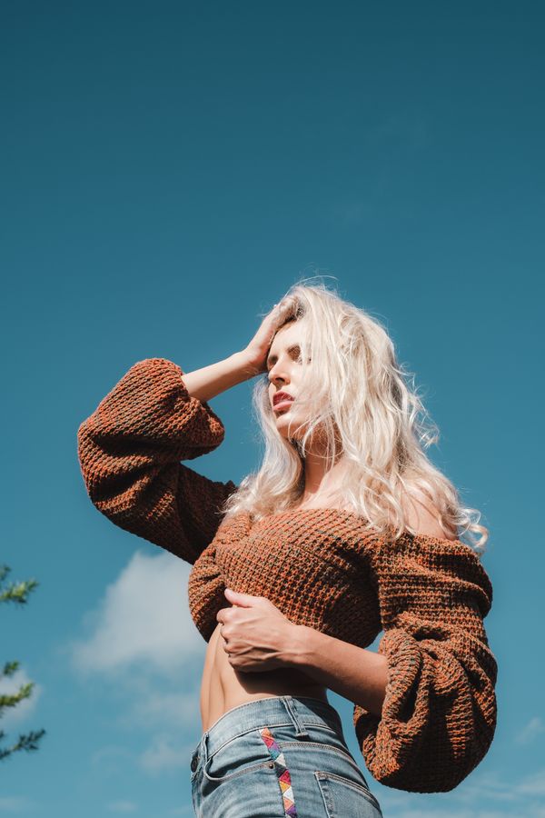 Woman wearing a walnut cropped sweater with high-waist jeans and a belt