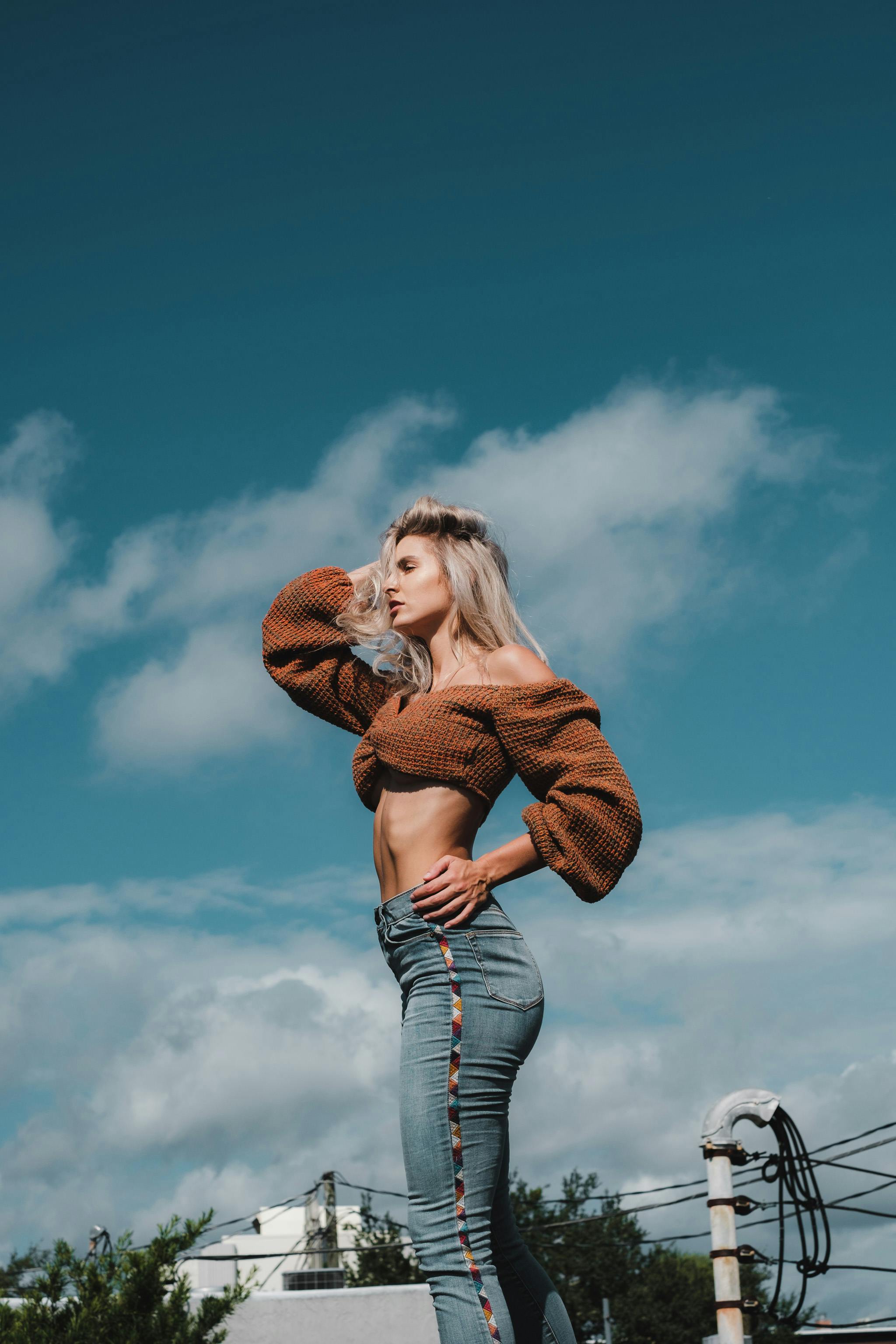 A Woman in Brown Crop Top and Denim Pants Posing beside a Gray Wall · Free  Stock Photo