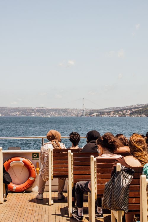 Free Passengers on a ferry boat enjoying a sunny day, with a scenic view of the sea and distant coastline. Stock Photo