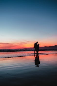 Silhouette of a couple walking along a Los Angeles beach at sunset, reflecting romance and serenity.