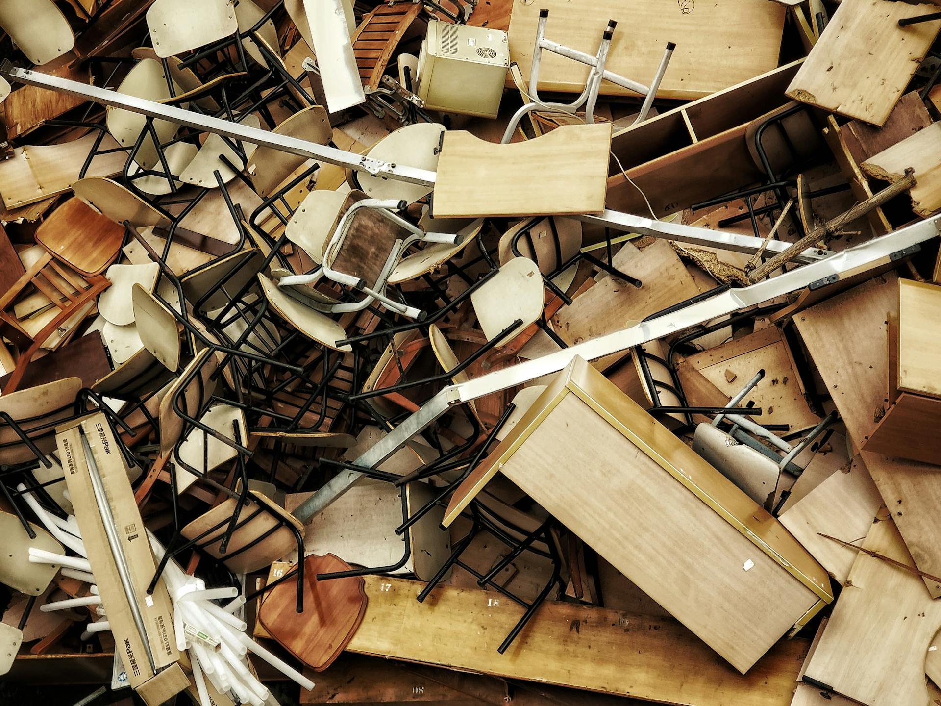 A chaotic pile of discarded wooden furniture and chairs seen from above.