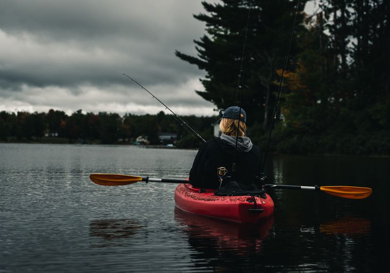 A kayaker fishing on a glassy lake at dawn