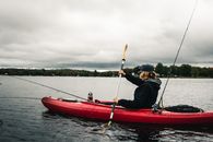 Man in Black Jacket and Black Pants Riding Red Kayak on Body of Water