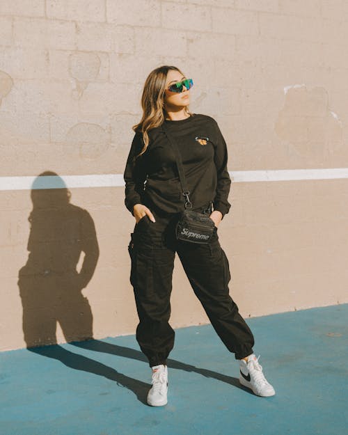 Woman in Black Long Sleeves Standing Beside a Wall