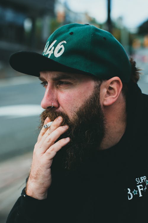 Man Wearing Green Baseball Cap Smoking Cigarette 