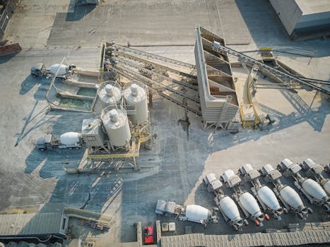 A drone-captured aerial view of an industrial concrete mixing plant with trucks and machinery.