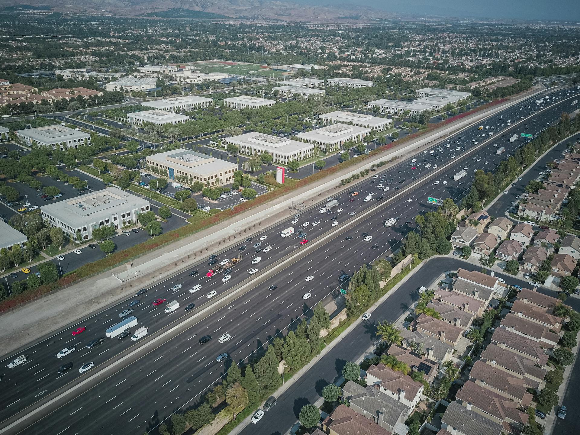 Drone shot capturing a busy highway and surrounding suburban landscape.