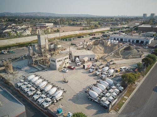 Free Aerial shot of a bustling cement manufacturing plant with mixer trucks and industrial equipment. Stock Photo