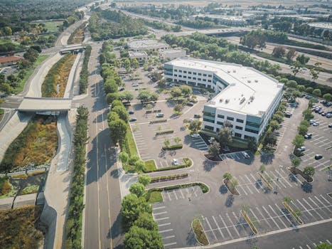 Aerial view of a suburban office building with empty parking lots and roads, captured in summer.