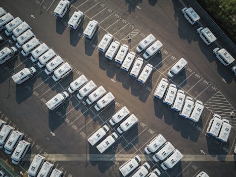 Aerial drone shot of neatly organized vans in a large parking lot.