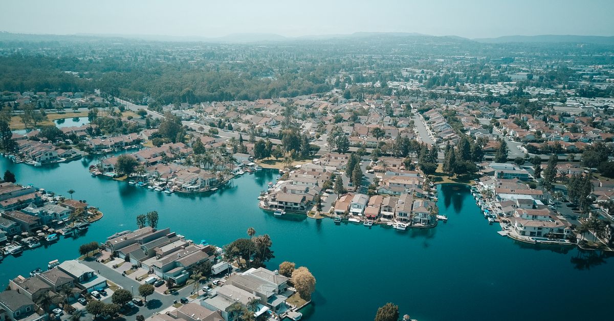 A scenic aerial view of lakeside homes in a suburban neighborhood surrounded by greenery.