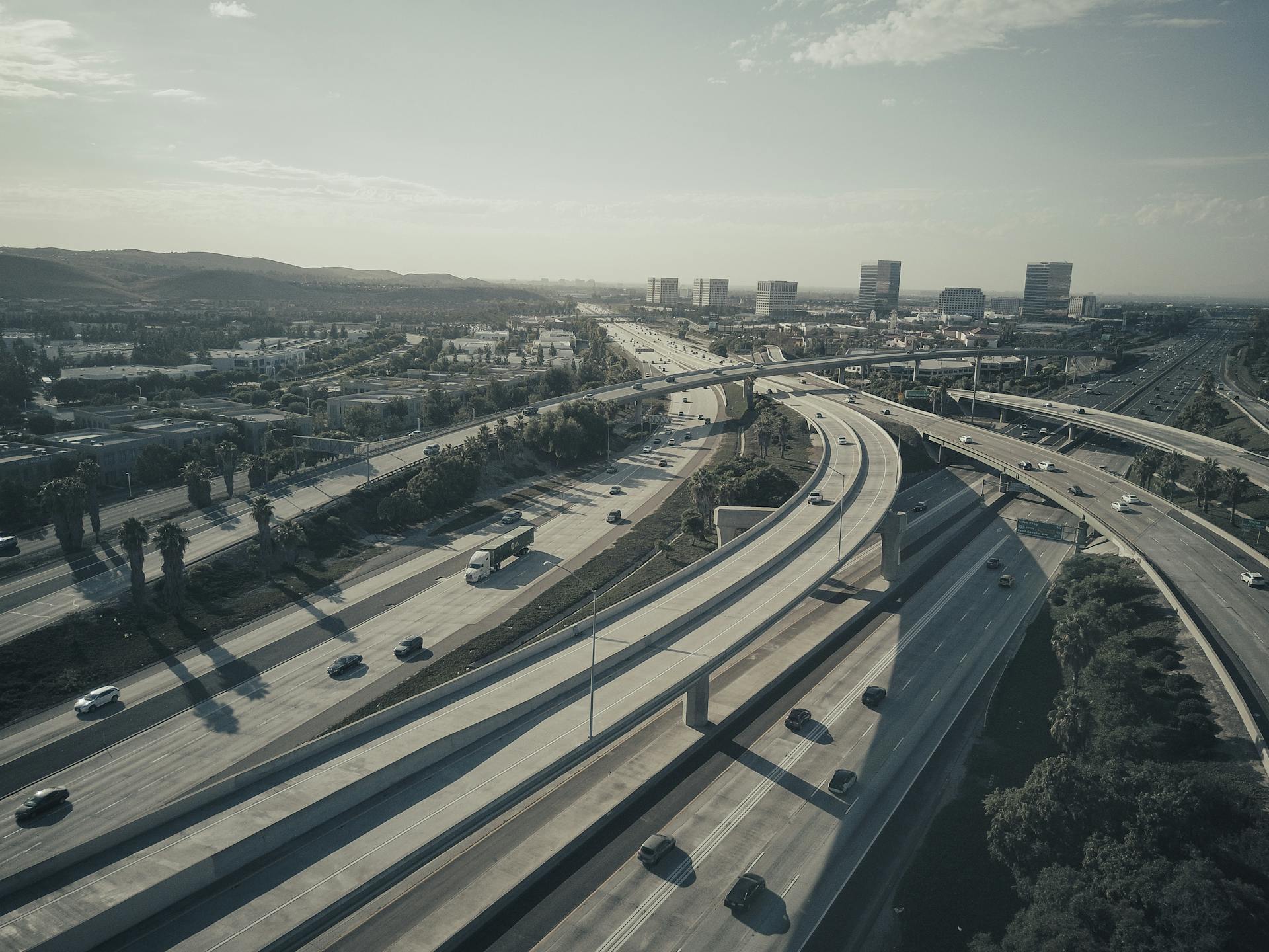 Drone shot of a sprawling highway intersection with moving cars under a cloudy sky.