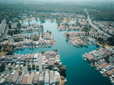 Scenic aerial view of a residential area with houses and water channels, surrounded by roads and greenery.