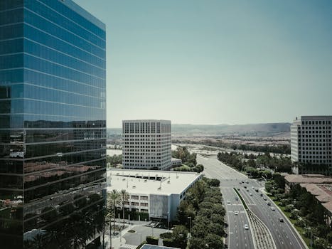 Aerial view of modern urban cityscape with skyscrapers and highways under clear sky.