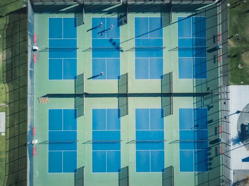 Free Drone shot of empty tennis courts with few players, top view perspective. Stock Photo