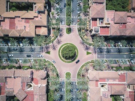 Aerial view of a vibrant cityscape featuring a roundabout with palm trees and urban infrastructure.