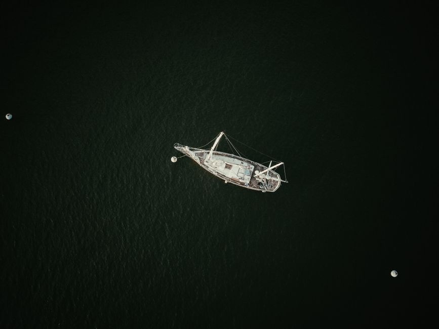 Stunning Waikiki Private Sunset Sail Romantic and Private Review: The Ultimate Hawaiian Sunset Experience Review 2026 - A drone shot of a solitary sailboat floating on dark, calm waters.