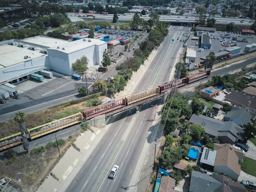 Free Aerial view of a cargo train crossing over a busy expressway in an urban area. Stock Photo