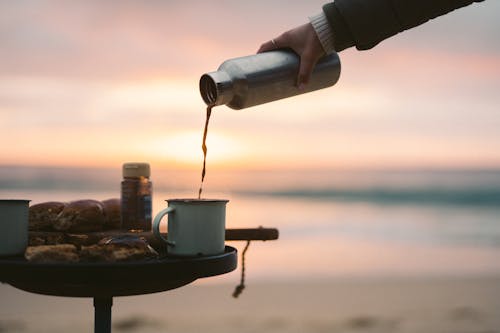 Person Pouring Hot Coffee on Mug