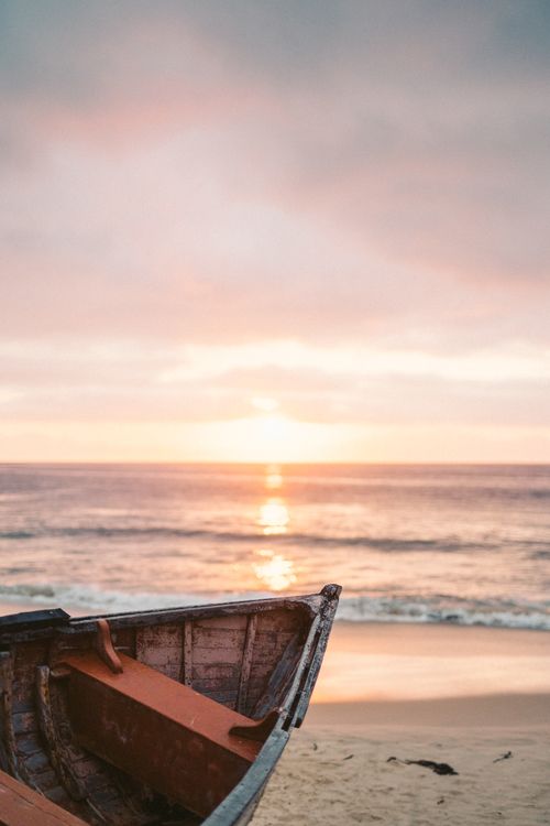 Free Wooden boat on a sandy beach at sunset, reflecting serene ocean views. Stock Photo