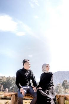 A couple sits together on a bench, enjoying a serene moment outdoors in Indonesia. - Fotografer Sidoarjo
