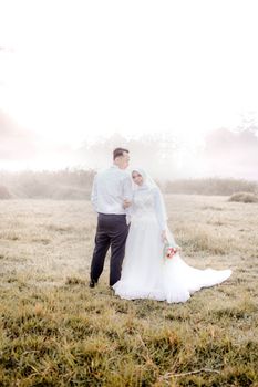 A couple embraces in an Indonesian field during their wedding photoshoot.