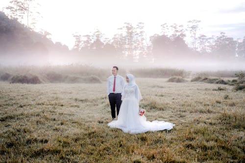 Bride and Groom Standing on Grass Fiield
