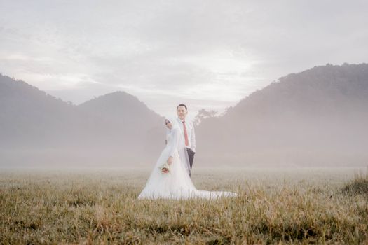 A newlywed couple poses in a misty Indonesian valley, capturing the essence of love and nature.
