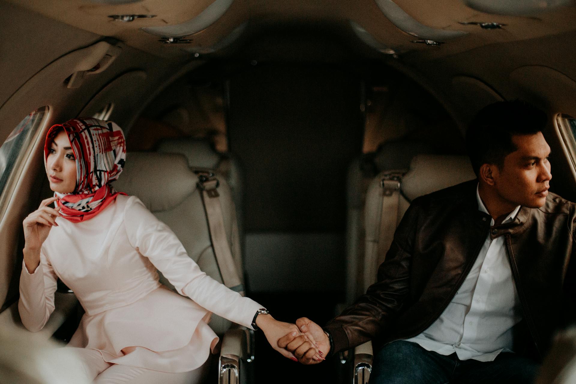 Elegant couple holding hands in a private jet, showcasing luxury travel.